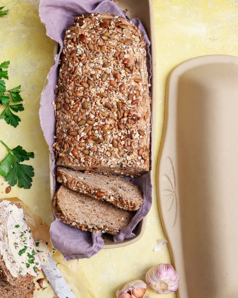 Shortbread and Tea Fall 2 Fresh whole grain bread in artisan covered bread pan with garlic and spread on side.