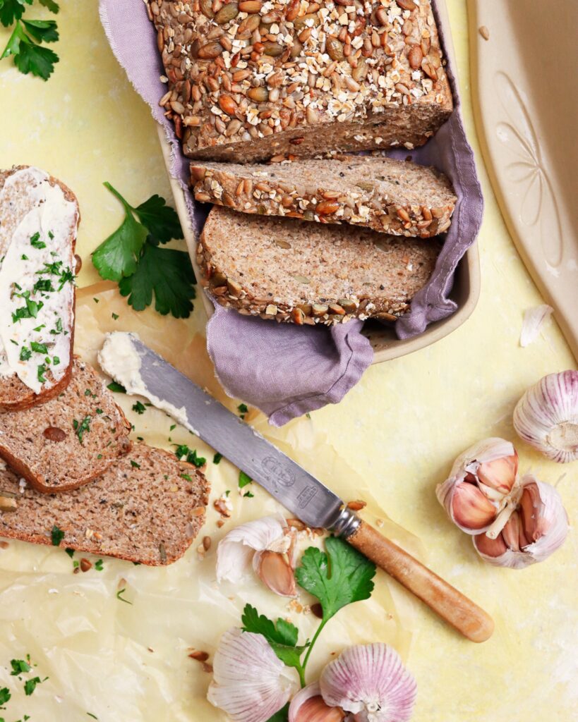 Shortbread and Tea Fall Fresh whole grain bread in artisan covered bread pan with garlic and spread on side.