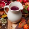 Cinnamon cider in stoneware pitcher with apples.