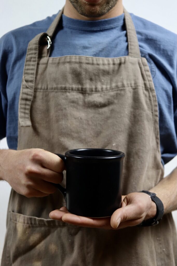 Hands holding Blackberry Brookline Cup in front of apron.