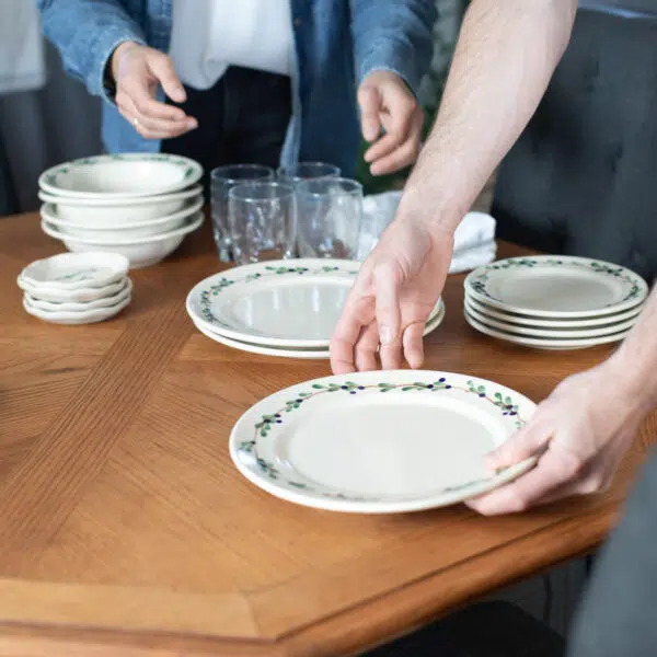 Friends setting a table with Blueberry Classic Dinnerware and coasters. Photo by Lauren Paige Photography.