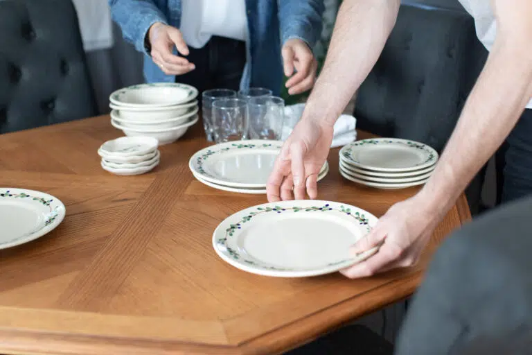 Friends setting a table with Blueberry Classic Dinnerware and coasters. Photo by Lauren Paige Photography.